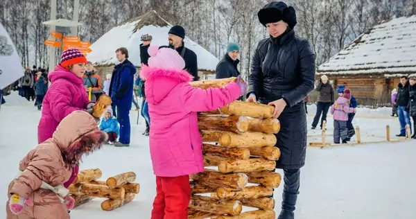 Дети и взрослые складывают бревна на Масленице в Этномире